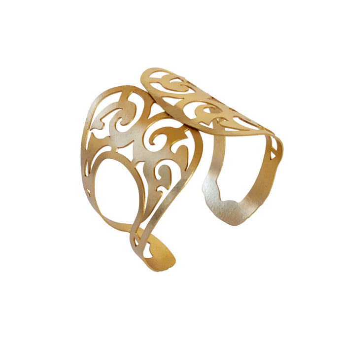 A gold-colored cuff bracelet with geometric openwork design, inspired by ancient Bactrian gold ornaments.