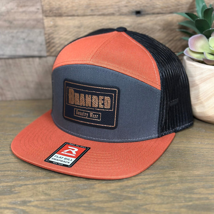 Branded Country Wear Leather Logo Patch 7 Panel Trucker Hat in Charcoal, Burnt Orange, & Black