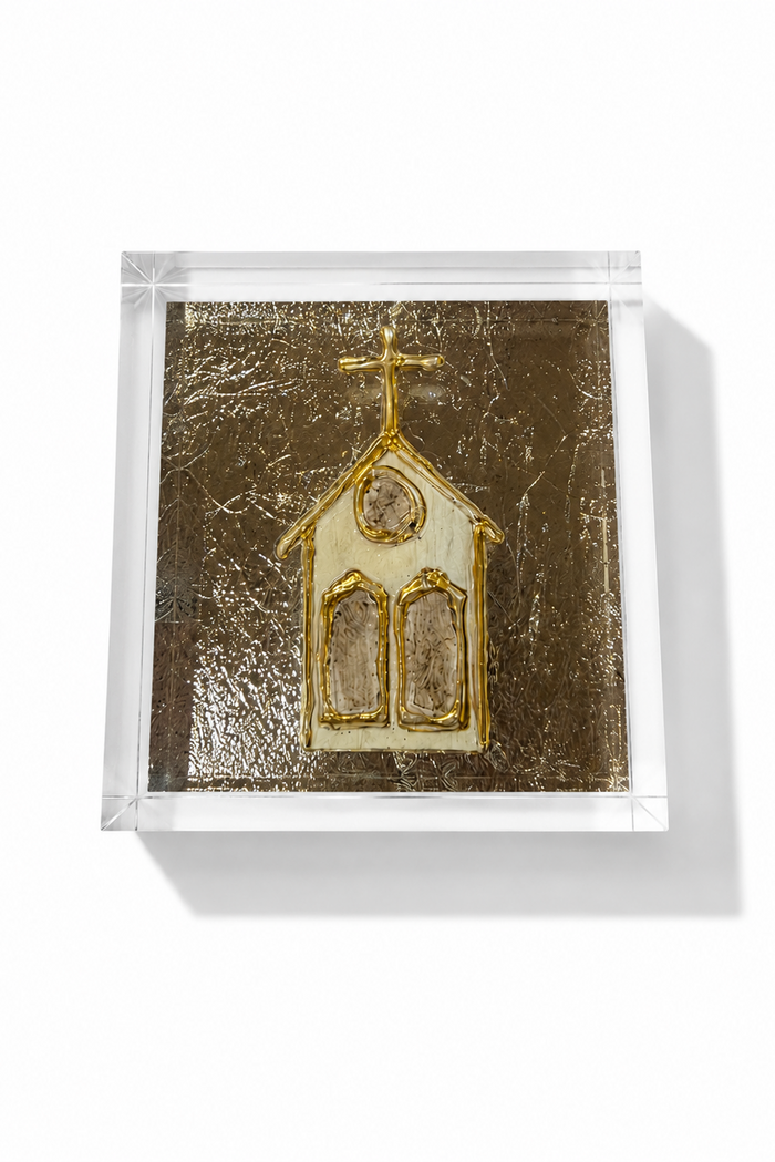 A square clear acrylic block containing a textured gold and cream church design, photographed from an angle on a white background with a soft shadow.
