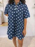 A woman wearing a short-sleeve denim shirt dress with a white polka dot pattern, standing in a brightly lit indoor setting.