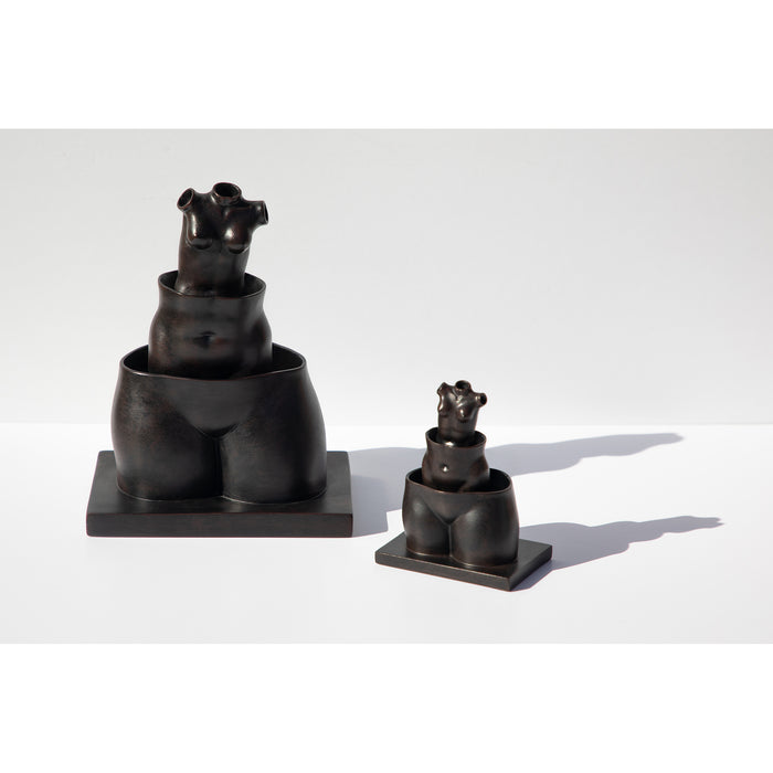 Two sculpture reproductions, one large and one small,  of René Magritte's La Folie Des Grandeurs featuring three hollow female forms stacked within each other.