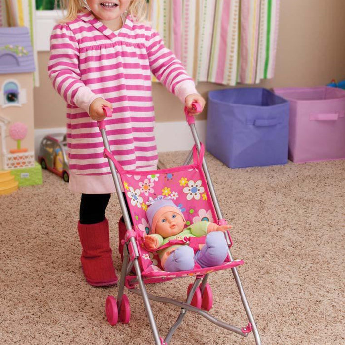 A young child pushes the My Sweet Baby Doll Stroller by My Sweet Baby, carrying a doll. The room has a beige carpet and colorful storage bins in the background.