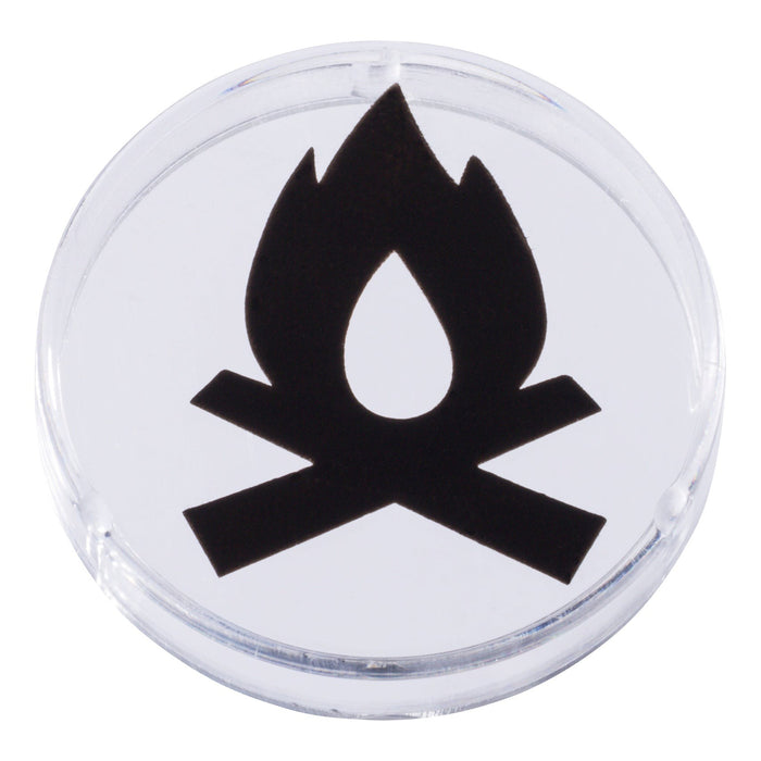 A clear round plastic token from Outdoor Discovery, featuring a black campfire icon with a flame above two crossed logs, perfect for imaginative play with the Outdoor Discovery Wildlife Tent Projector. Displayed on a white background.