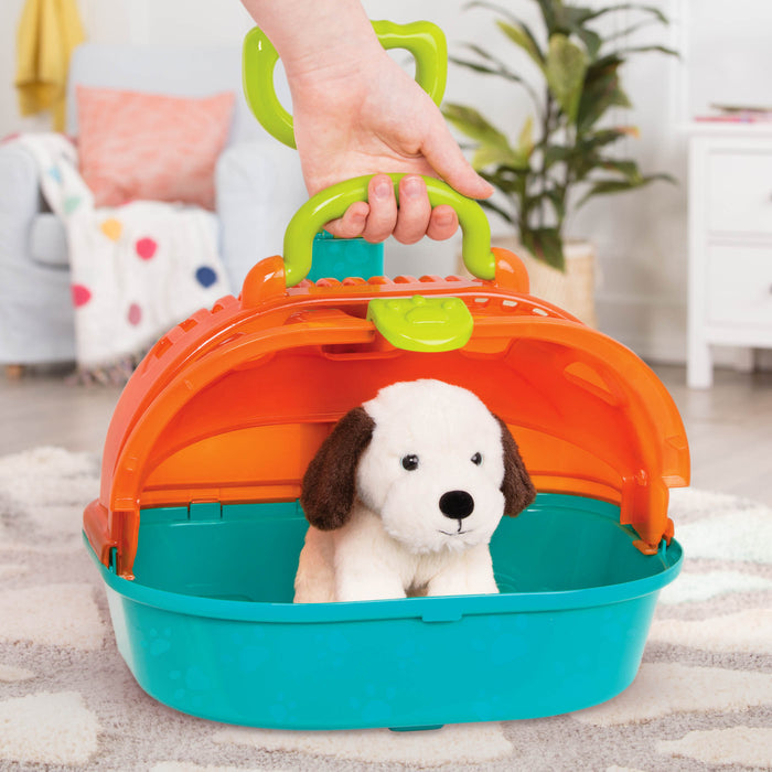 A toy pet carrier with a plush puppy inside and vet tools surrounding it.