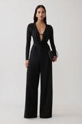 Woman wearing black cowl long sleeve slinky bodysuit, with black pants.