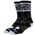 A pair of crew socks featuring a black and olive green camouflage pattern, with white text reading 'SKATE IN THE WOODS' on the upper cuff and white accents on the toes and heels, set against a plain white background.