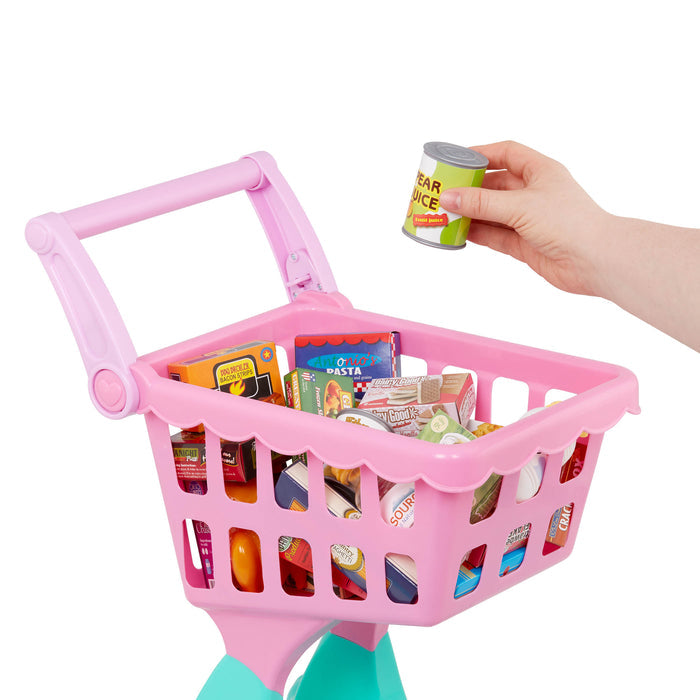 A pink and green toy shopping cart full of groceries.