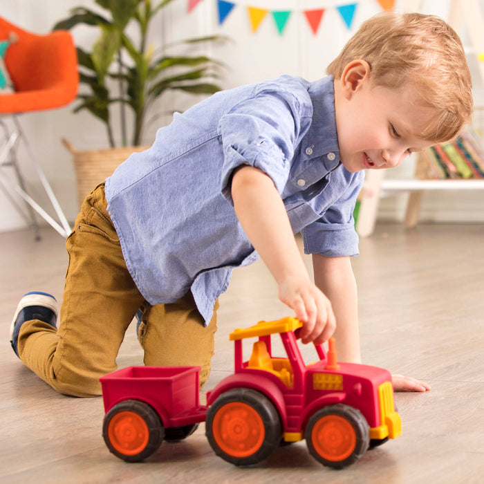 A red tractor toy with a detachable trailer.
