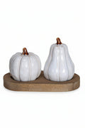 A decorative ceramic set featuring a ribbed white pumpkin and a pear-shaped white vessel, both with brown stems, displayed on a round wooden base against a white background.