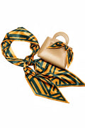 Beige handbag with a green and orange patterned scarf draped over it on a white background
