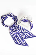 Blue and white patterned scarf draped over a white bottle with a white background