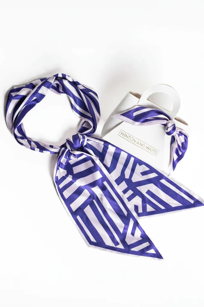 Blue and white patterned scarf draped over a white bottle with a white background