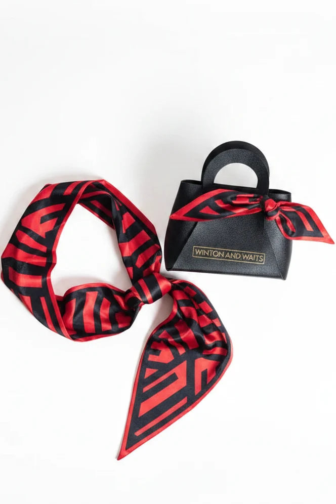 Red and black patterned scarf with a black handbag on a white background