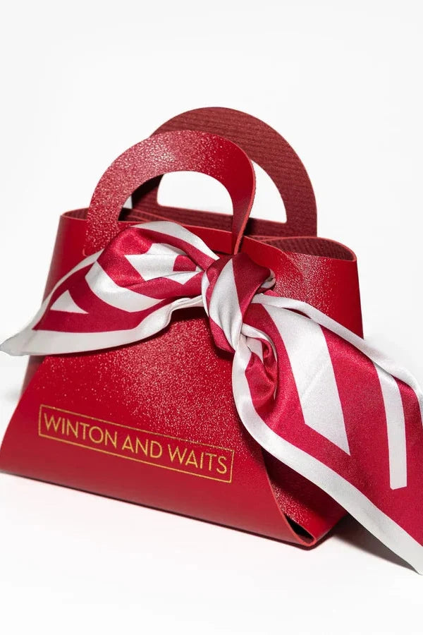Red handbag with a white scarf and 'Winton and Waits' branding on a white background